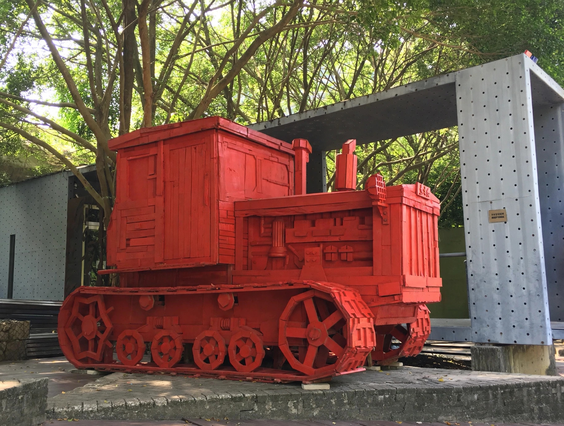 Side view of The East Is Red, a monumental tractor sculpture assembled from discarded wood